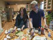 Dr. Hoa Ly, right, and his wife, Chi, prepare the table for a traditional Vietnamese meal Wednesday at their Vancouver home. Hoa and Chi both came to the U.S. as refugees after the Vietnam War.