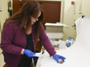 Elaine Dorset, an archeologist at Fort Vancouver, handles an 1942 Army service Forces patch.