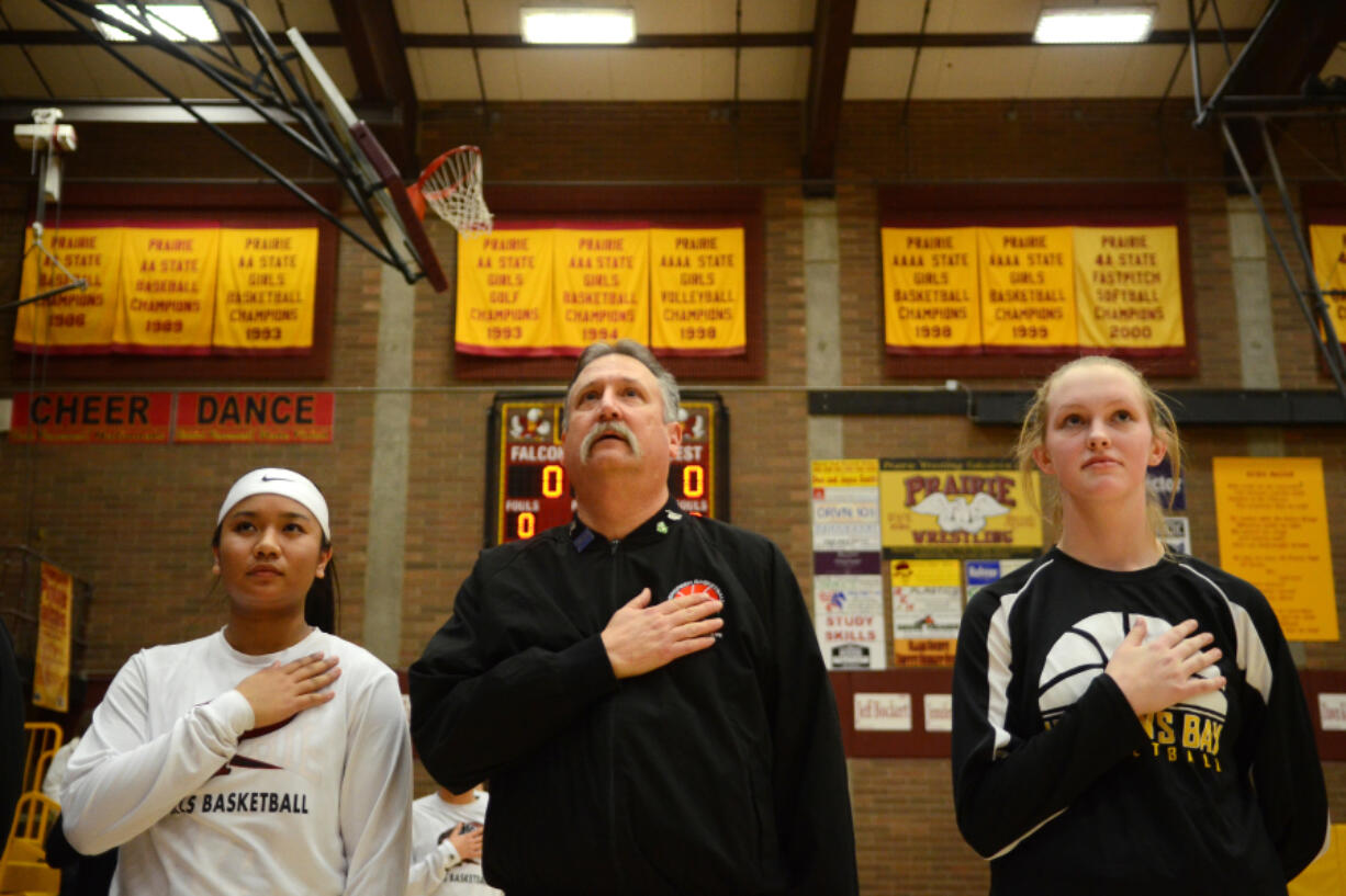 Rick Stover is flanked by Prairie senior Grace Prom, left, and Hudson&#039;s Bay senior Sharon Hanson during the national anthem before a basketball game at Prairie on Thursday. It&#039;s tradition that started last season with players flanking Stover to help remember the sacrifice Stover&#039;s late son Chris made in service to his country.