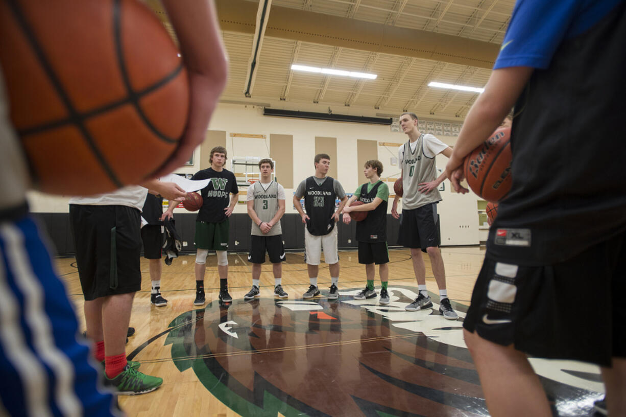 Senior Bryce Mulder (0) joins teammates as they talk things over during practice at Woodland High School on Wednesday afternoon, Feb. 22, 2017.