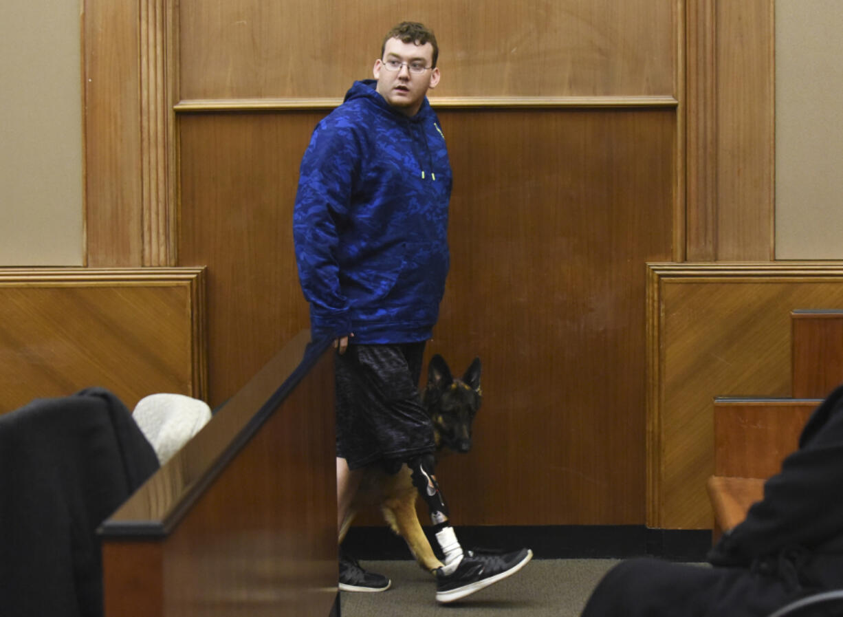 Justin Carey, who was struck by a vehicle while waiting for the school bus in 2013, steps down from the witness stand with his service dog, Shiva, on Wednesday afternoon during the vehicular assault retrial for Shaun Johnson in Clark County Superior Court.