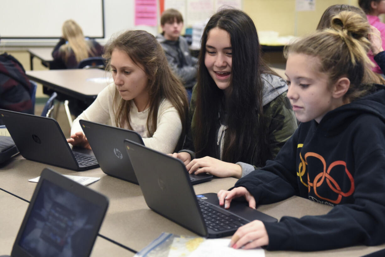 Seventh-graders Katerina Yarosh, left, Rachel Knight, and Emma Jensen work on their new Chromebooks during study hall at Pleasant Valley Middle School on Thursday.