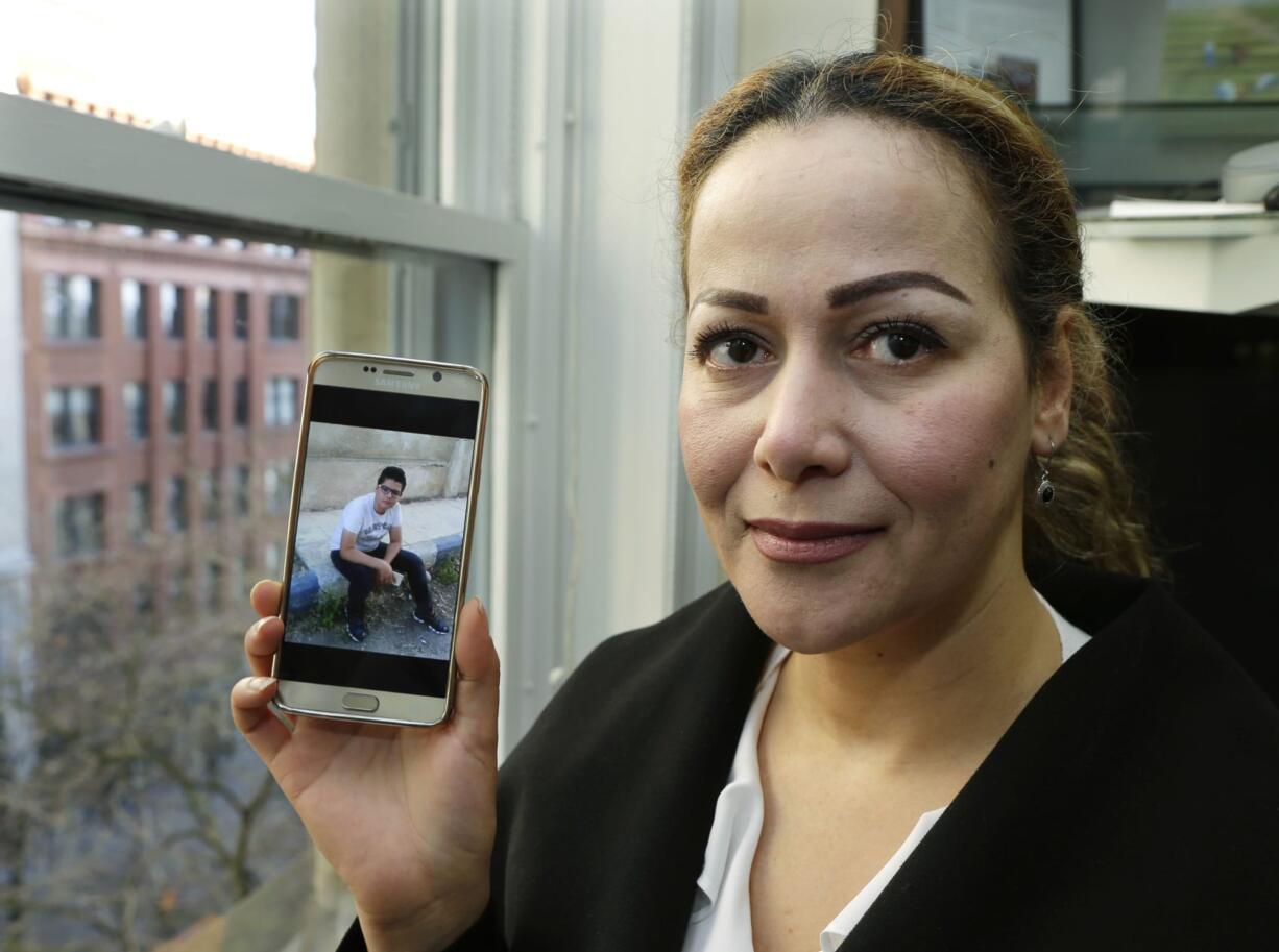 Reema Duhman poses for a photo Wednesday, Feb. 1, 2017, in the offices of the Northwest Immigrant Rights Project in Seattle with a photo of her son displayed on her phone. Duhman, who fled war-torn Syria and now is a lawful permanent U.S. resident who lives in Seattle, had almost completed the complicated process of securing a visa for her 16-year-old son, who is still in Syria, when President Donald Trump issued an executive order prohibiting anyone from Syria and six other countries from traveling to the U.S. Duhman is a plaintiff in a federal class-action lawsuit filed this week by the Northwest Immigrant Rights Project that says Trump's order is unconstitutional and a violation of the Immigration and Nationality Act. (AP Photo/Ted S.