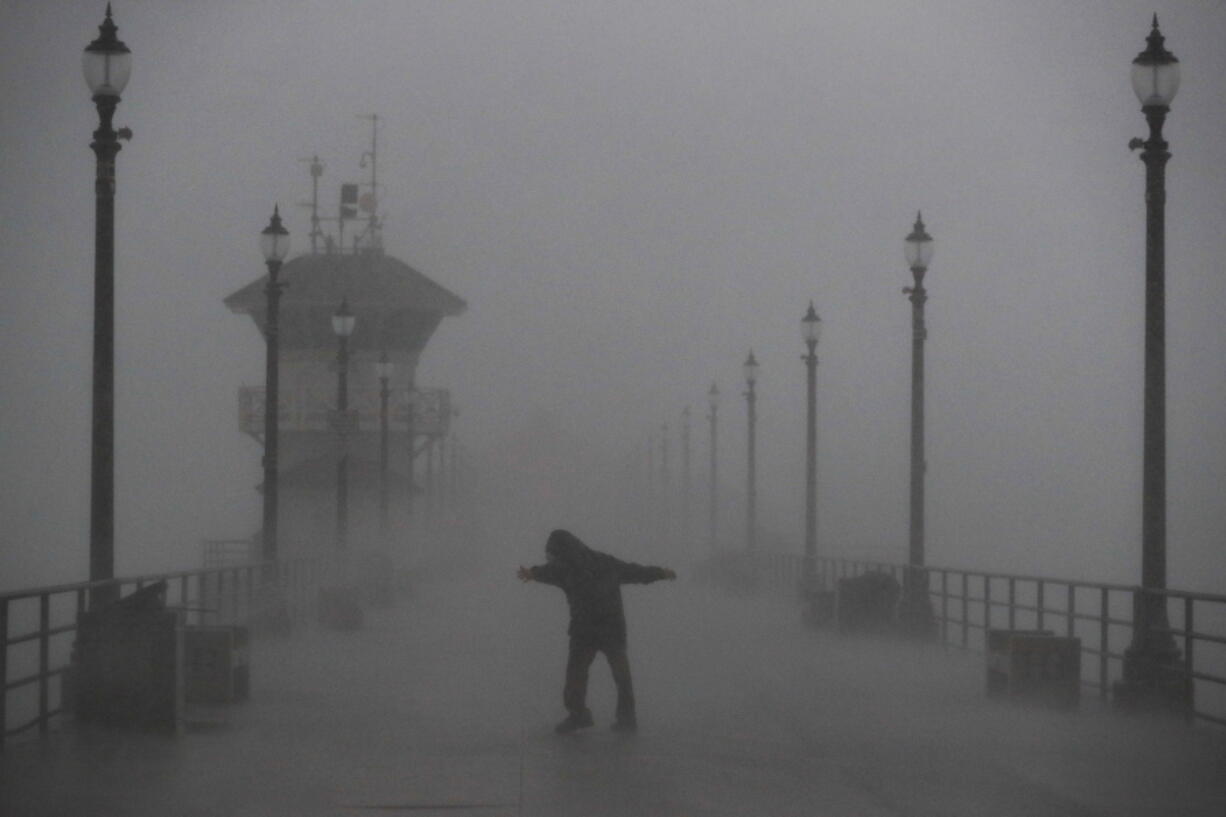 A man struggles against heavy wind and rain Friday on a pier in Huntington Beach, Calif. (JAE C.