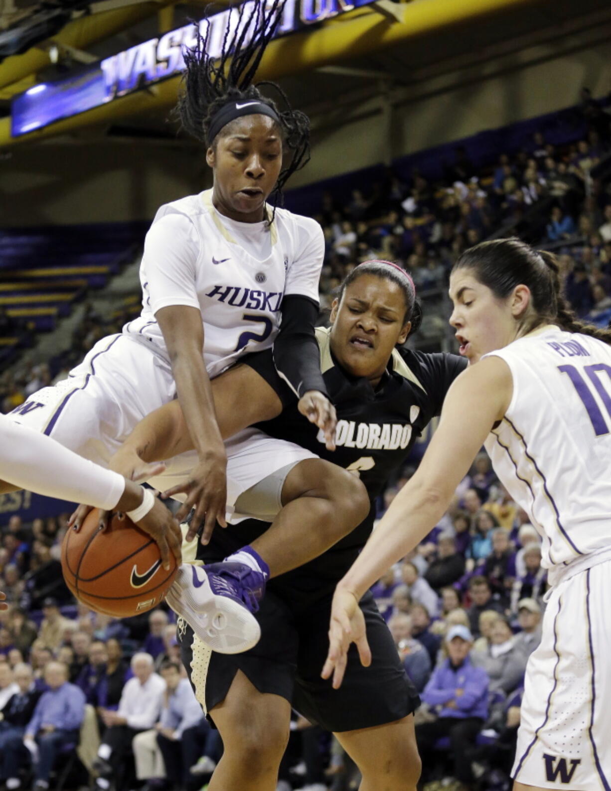 Washington&#039;s Aarion McDonald, left, leaps across Colorado&#039;s Bri Watts, center, Thursday in Seattle.