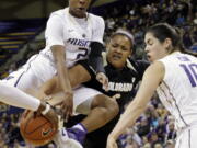 Washington&#039;s Aarion McDonald, left, leaps across Colorado&#039;s Bri Watts, center, Thursday in Seattle.