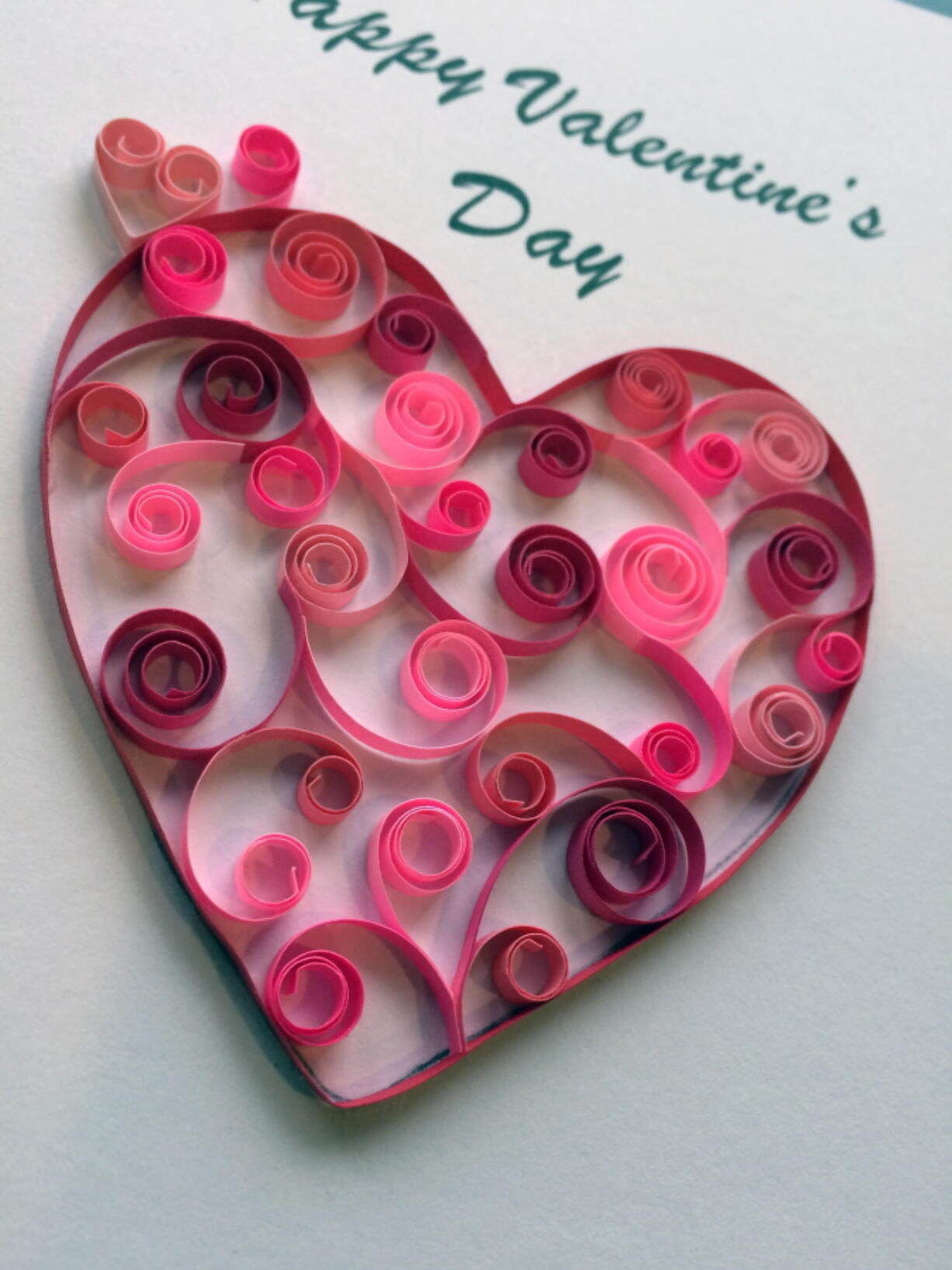 Open coil scrolls in various shades of red and pink combine to create a heart shaped message.