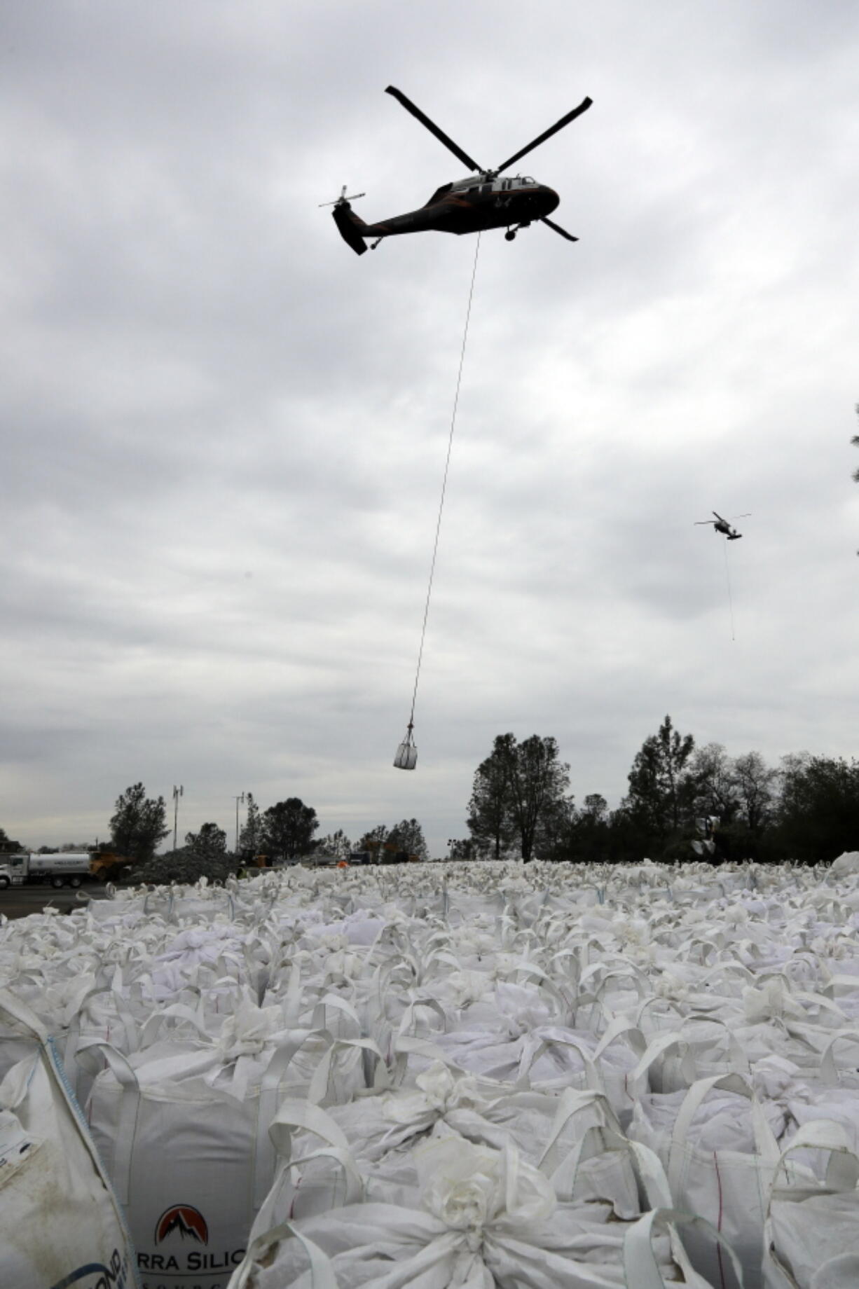 A helicopter carries sandbags toward the damaged Oroville Dam on Wednesday in Oroville, Calif. The Oroville reservoir is continuing to drain as officials scramble to reduce the lake&#039;s water level.