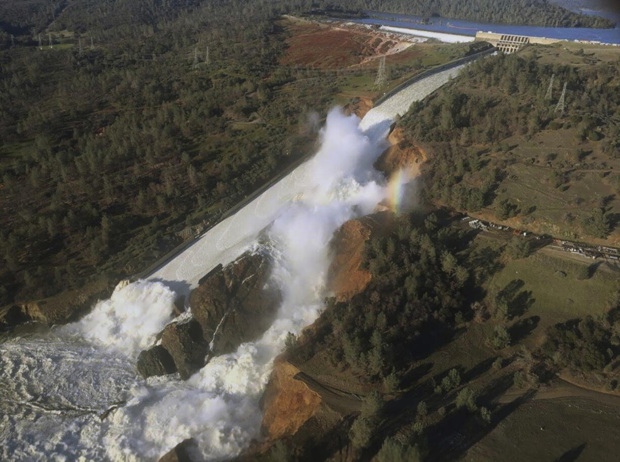 The damaged spillway with eroded hillside in Oroville, Calif. California water authorities will cut the outflow from the dam to allow workers to remove debris piled at the base of its main spillway.