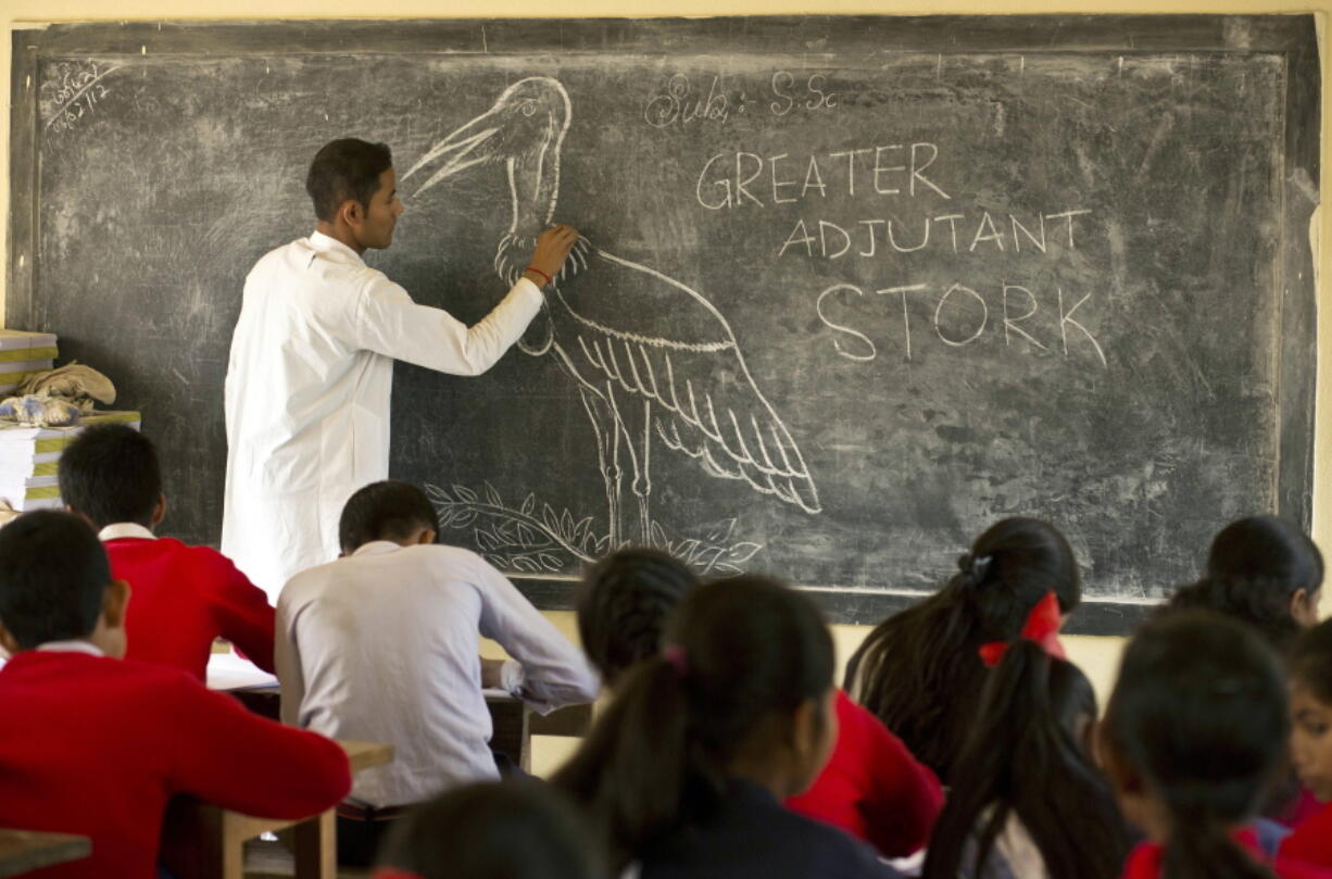 A teacher of Sankardev Sishu Niketan school draws a greater adjutant stork on a blackboard at Dadara village, west of Gauhati, India.