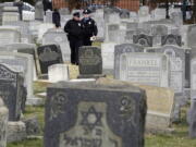 Philadelphia Police walk through Mount Carmel Cemetery on Monday in Philadelphia. More than 100 headstones have been vandalized at the Jewish cemetery in Philadelphia, damage discovered less than a week after similar vandalism in Missouri, authorities said.