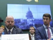 Olympic swimming champion Michael Phelps listens at right as Olympic shot-put champion Adam Nelson holds up his gold medal as they testify on Capitol Hill in Washington on Tuesday before the House Commerce Energy and Commerce subcommittee hearing on the international anti-doping system.