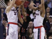 Pacific guard K.J. Smith, center, tries to shoot between Gonzaga forward Zach Collins (32) and forward Johnathan Williams (3) during the first half of an NCAA college basketball game in Spokane, Wash., Saturday, Feb. 18, 2017.