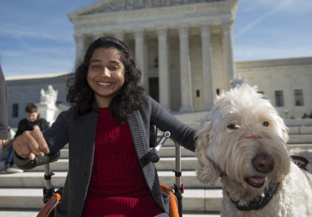 Ehlena Fry of Michigan, sits with her service dog Wonder, while speaking to reporters outside the Supreme Court in Washington in October.