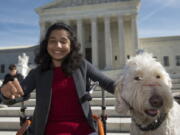 Ehlena Fry of Michigan, sits with her service dog Wonder, while speaking to reporters outside the Supreme Court in Washington in October.