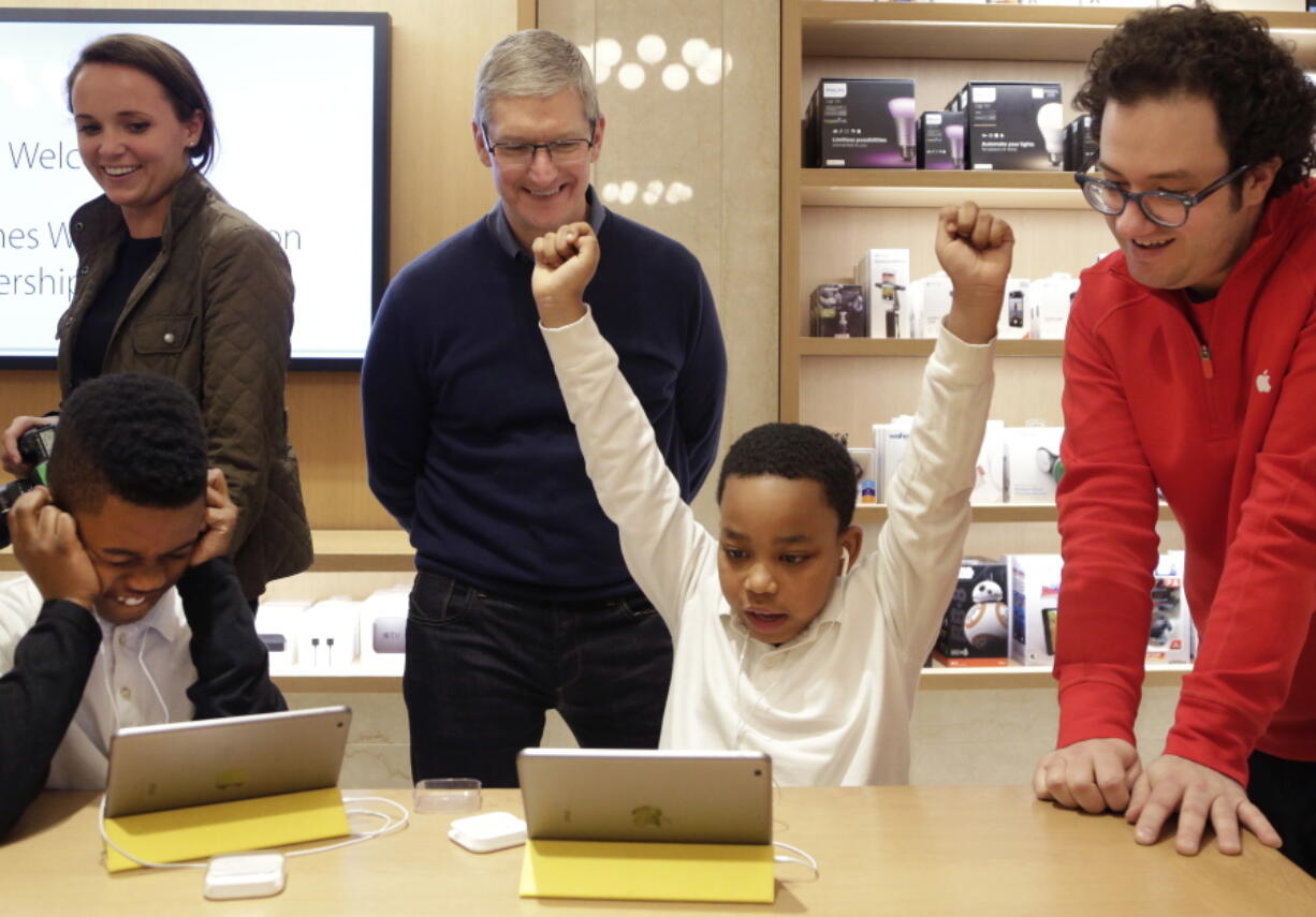 Jaysean Erby raises his hands Dec. 9, 2015, as he solves a coding problem while Apple CEO Tim Cook watches from behind at an Apple Store in New York as Apple hosted Hour of Code events around the world.