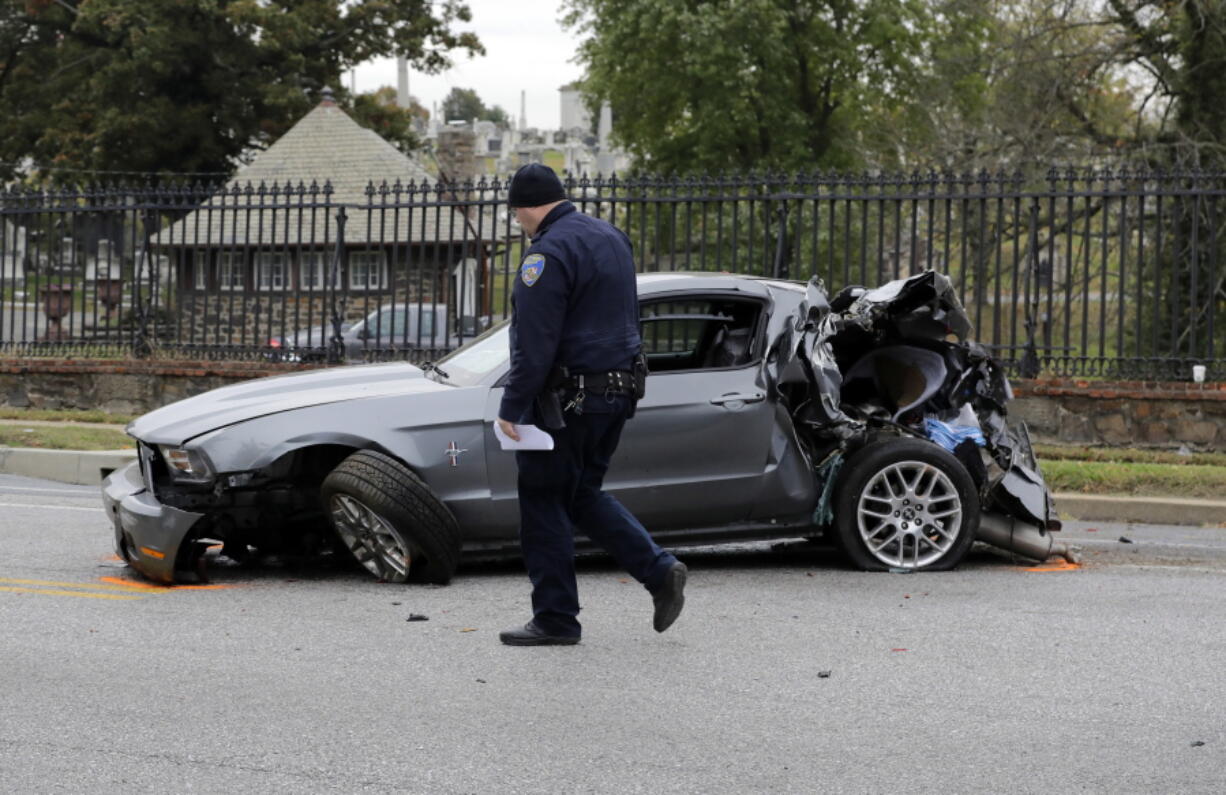 FILE - In this Nov. 1, 2016 file photo, a member of the Baltimore Police Department walks past a car that was damaged by a school bus before the bus was involved in a fatal collision with a commuter bus in Baltimore. A jump in traffic fatalities last year pushed deaths on U.S. roads to their highest level in nearly a decade, erasing improvements made during the Great Recession and economic recovery, a leading safety organization said Wednesday, Feb. 15, 2015.  (AP Photo/Patrick Semansky.