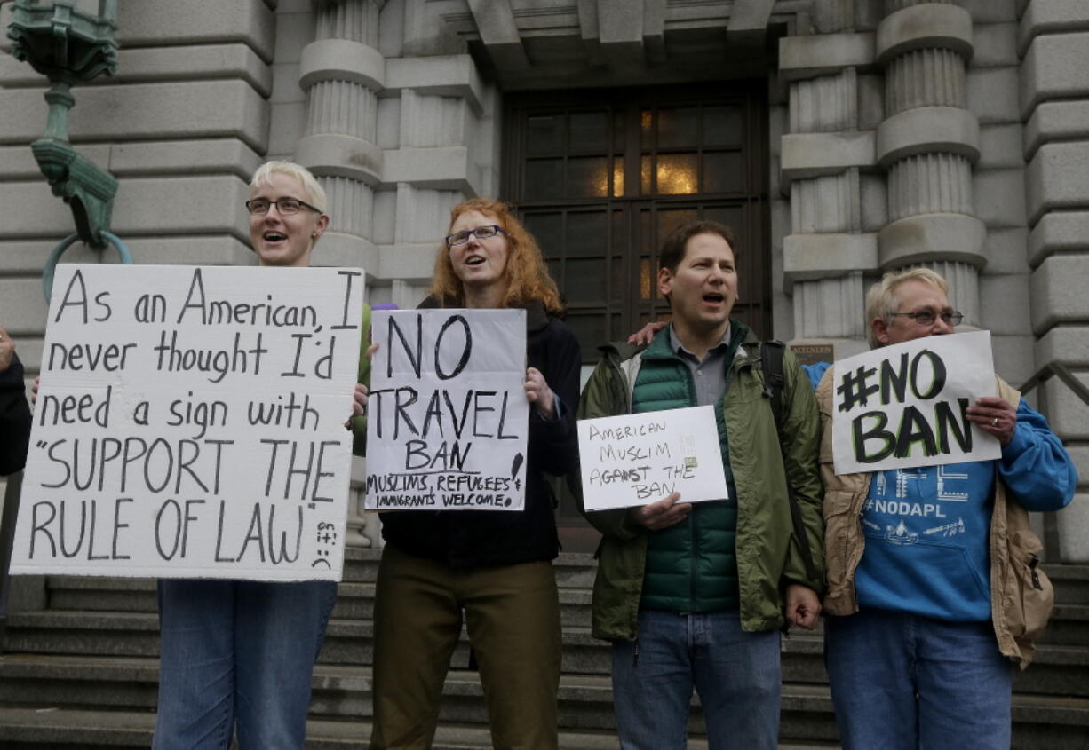 Kay Aull, from left, holds a sign and chants with Beth Kohn, Paul Paz y Mino and Karen Shore outside of the 9th U.S. Circuit Court of Appeals in San Francisco on Tuesday. President Donald Trump&#039;s travel ban faced its biggest legal test yet Tuesday as a panel of federal judges prepared to hear arguments from the administration and its opponents about two fundamentally divergent views of the executive branch and the court system.