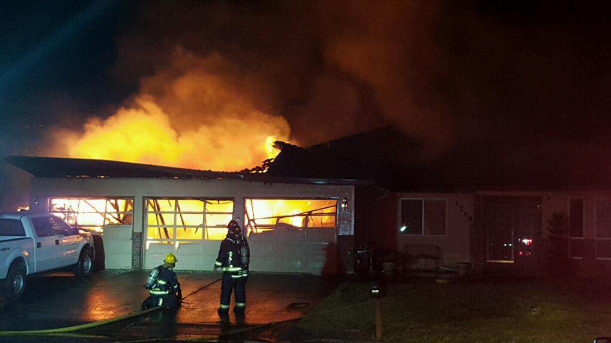 Firefighters douse flames to contain a fire that started early Wednesday morning, Feb. 1, 2017, at a Washougal home.