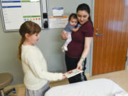 Kamryn Reilly, 8, donates the book &quot;Ladybug Girl Plays&quot; to 9-week-old Lucy Pimentel, held by her mother, Cammy Torres, at Legacy Salmon Creek Medical Center.