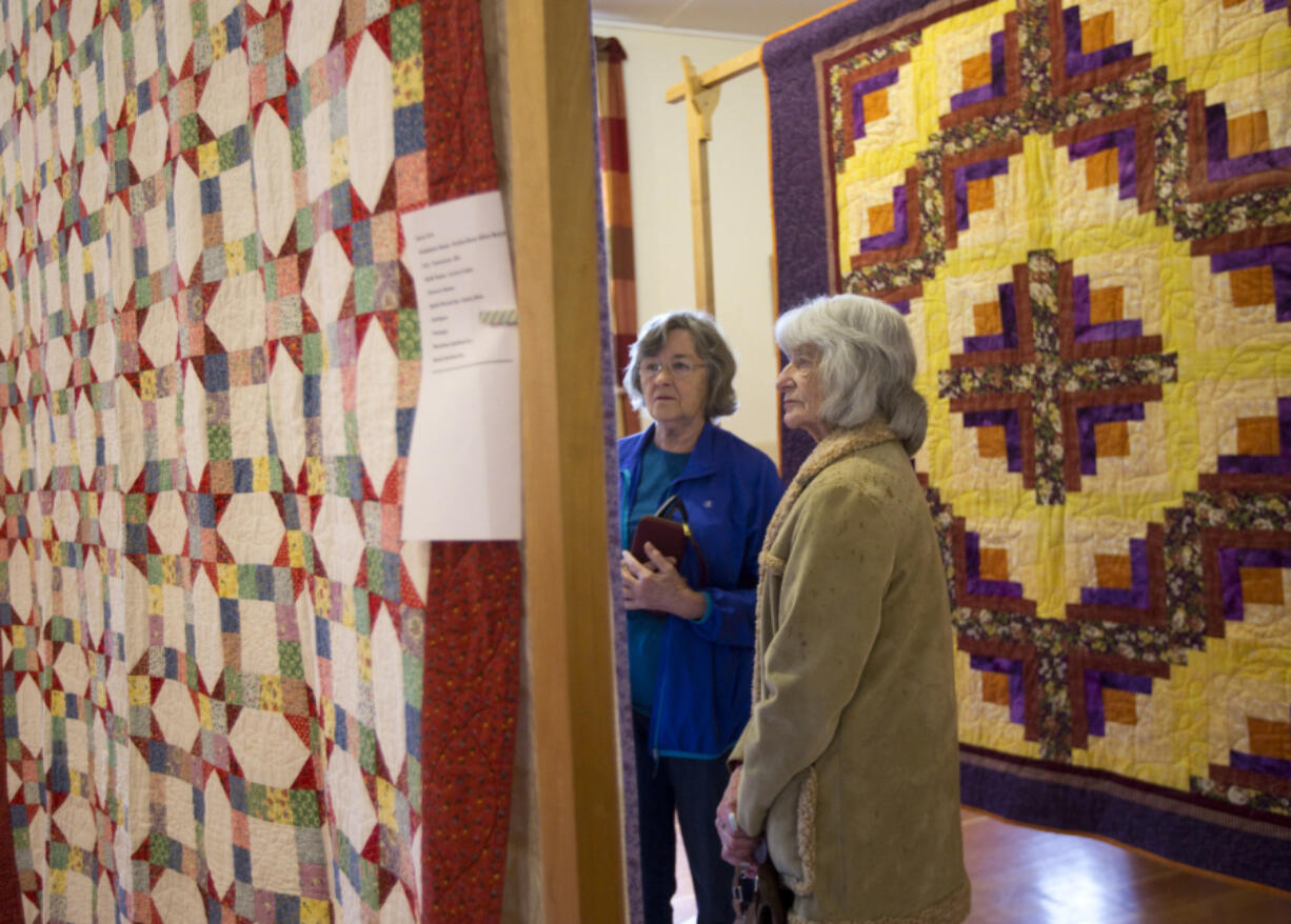 Evelyn Dobbins, left, and Ruth Ham examine quilts on display as part of the North Clark County Historical Museum&#039;s quilt show Sunday in Amboy. These quilts were set up at the Mt. Valley Grange hall.