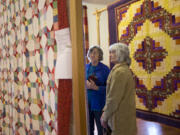 Evelyn Dobbins, left, and Ruth Ham examine quilts on display as part of the North Clark County Historical Museum&#039;s quilt show Sunday in Amboy. These quilts were set up at the Mt. Valley Grange hall.