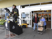 Larry Langdon, center, and Sheila Langdon, right, exit the Fisher&#039;s Landing Fred Meyer on Southeast McGillivray Boulevard, where Vancouver firefighter Scott Woodhouse uses a stair climber as part of a fundraiser for the Leukemia &amp; Lymphoma Society on March 3.