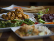 Crispy orange chicken, clockwise from dish in focus, is served with egg roll fries, crispy beef, Pad Thai and Buddha mix vegetables at Fast Thai in Southeast Vancouver.