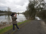 Hyunmi Holeman of Vancouver takes a photo of a flooded section of the Salmon Creek Greenway Trail during a walk on Monday afternoon. Minor flooding of the Columbia River caused parts of the trail to flood as water backed up into Salmon Creek.