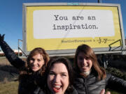 The Joy Team&#039;s Chief Joy Officer Michele Larsen, center, with co-workers Leanne Reid, left, and Megan Streeter in front of one of the organization&#039;s older billboards in Vancouver.