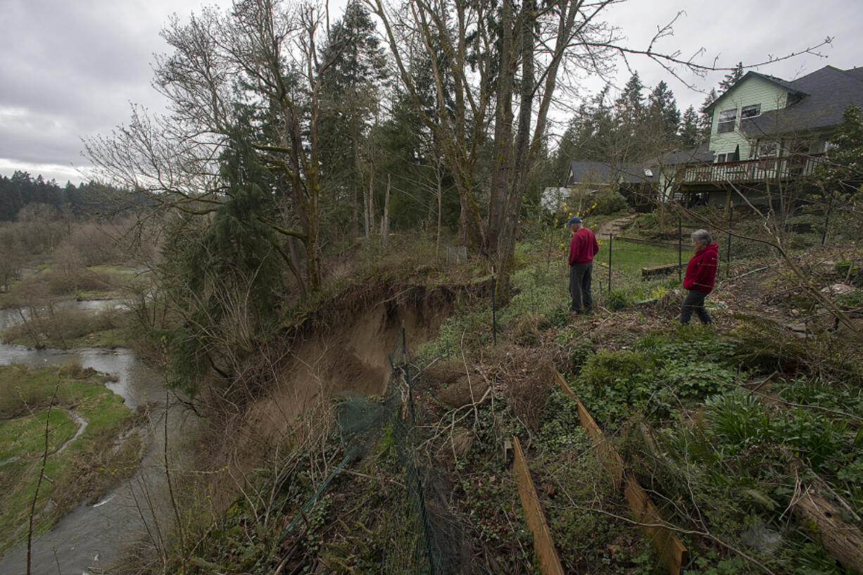 Clancy Kelly, left, and his neighbor Sarah Athay examine the aftermath of a landslide that occurred behind their Salmon Creek homes on Friday. For the past two years, a handful of slides have gnawed away at the slope behind their homes.