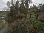 Clancy Kelly, left, and his neighbor Sarah Athay examine the aftermath of a landslide that occurred behind their Salmon Creek homes on Friday. For the past two years, a handful of slides have gnawed away at the slope behind their homes.