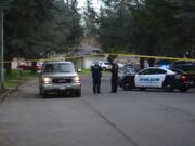 Officers direct a neighboring resident past a roadblock set up for a shooting investigation down the road Sunday evening on Northeast 140th Avenue. The Vancouver Police Department said officers responded to a report of a shooting in the area and found two dead men at a residence in the 1500 block.