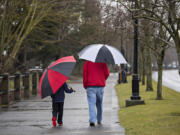 Beckett Ince, 8, of Ridgefield, left, keeps in step with his dad, Jubal, as they enjoy a soggy stroll together along the Vancouver Waterfront on the afternoon of Feb. 8.