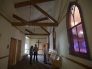 Centennial committee members Linda Bieker and Dean Sutera, from left, discuss plans with the Rev. Korey Finstad, pastor of Bethel Lutheran Church. The windows behind him mark what had been an exterior wall of the original church, which was built in 1921. The Brush Prairie church is celebrating the 100th anniversary of its formation.