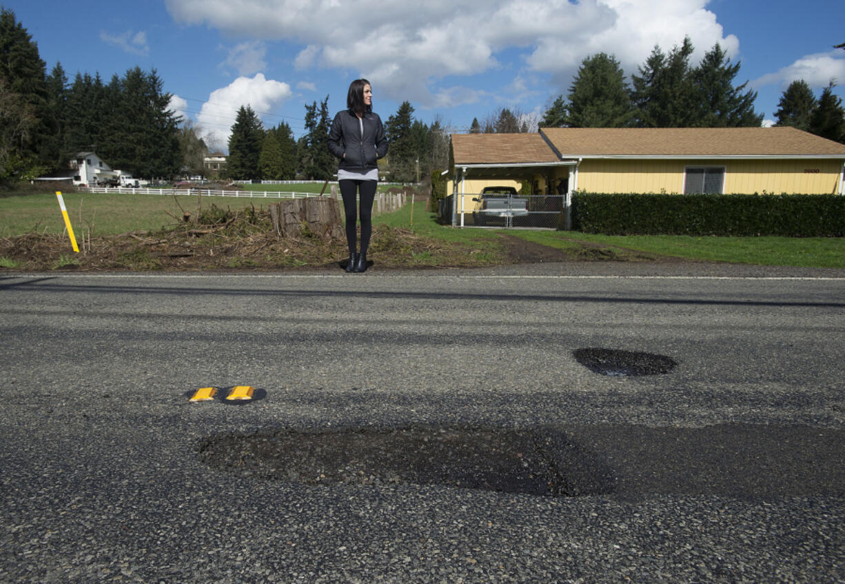 Vancouver resident Teresa Eldred stands near a pothole along Northeast 68th Street that she said popped her tire and damaged her rim early last month. She filed a tort claim against the county to recoup her costs but was denied --  like most everyone else who files claims against the government about pothole damage.