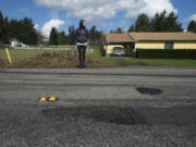 Vancouver resident Teresa Eldred stands near a pothole along Northeast 68th Street that she said popped her tire and damaged her rim early last month. She filed a tort claim against the county to recoup her costs but was denied --  like most everyone else who files claims against the government about pothole damage.