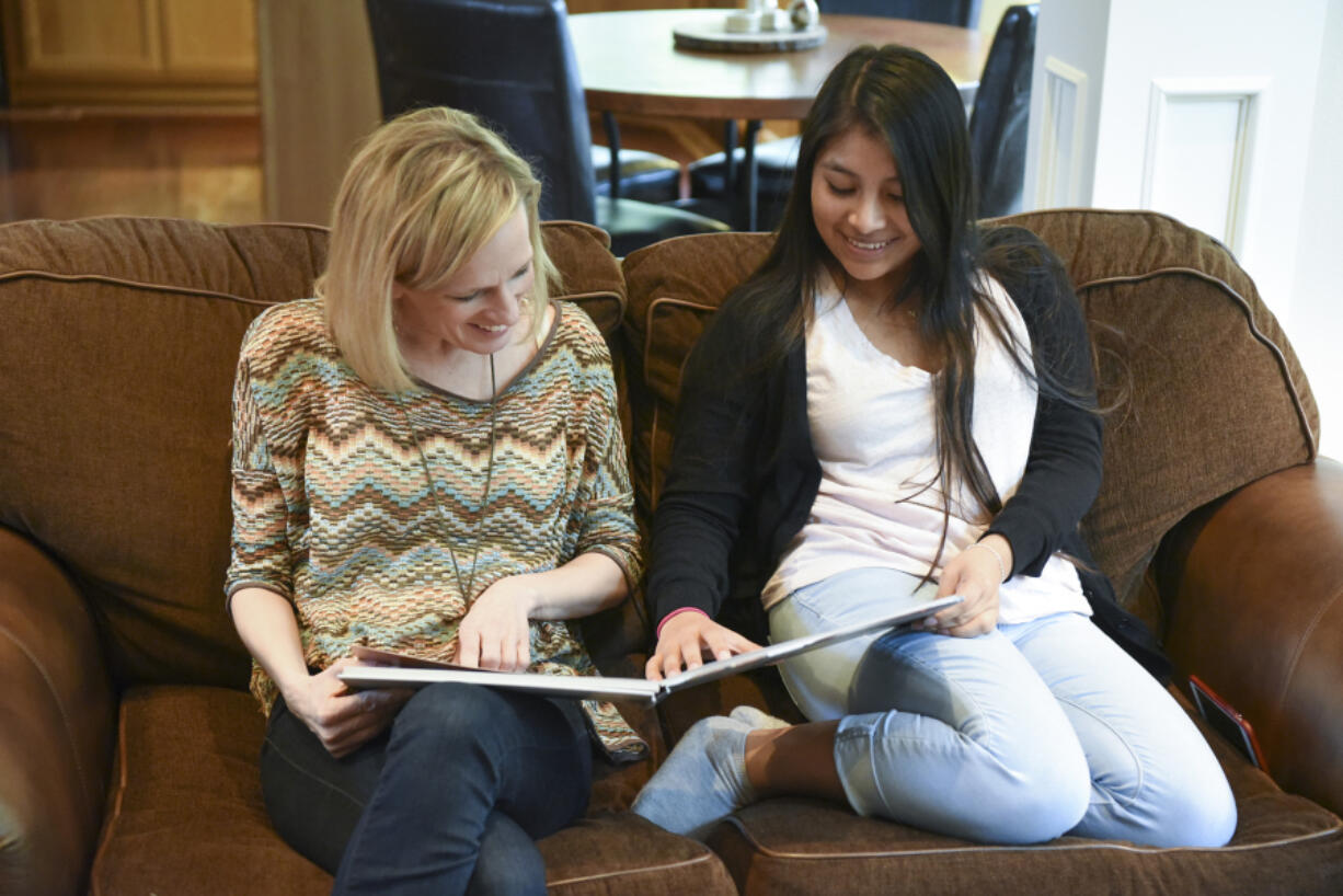 Heather Radu, founder of Dorie&#039;s Promise, an orphanage in Guatemala, left, looks at a photo album of the orphanage with Nallely Lux, 19, at Radu&#039;s home in Camas. Lux, the first orphan from Dorie&#039;s Promise to obtain a visa and move to the United States, currently lives in Vancouver and is enrolled at Clark College.