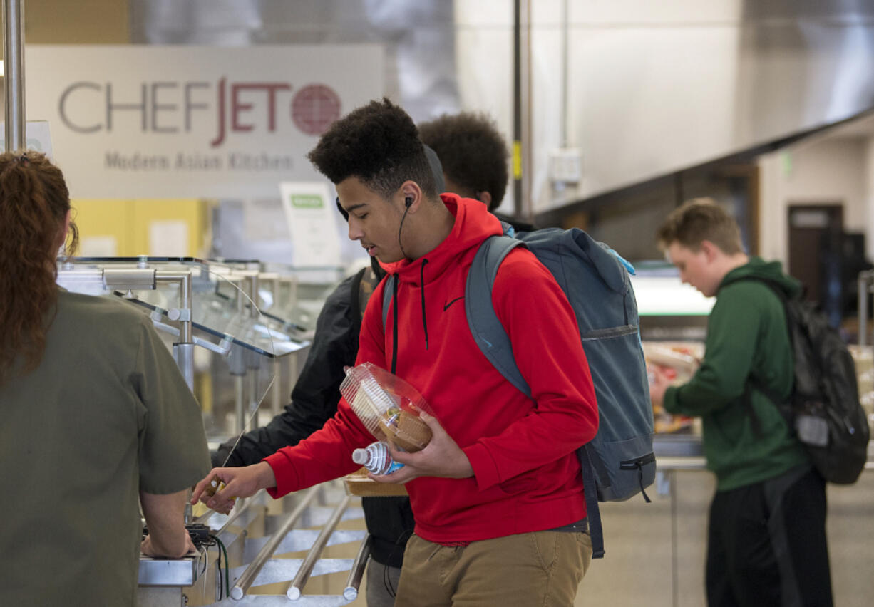 Freshman DeAndre Hampton, 15, listens to music as he picks up a meal after school at Evergreen High School on Tuesday afternoon. Students receive free meals after school to help fuel them for their evening activities.