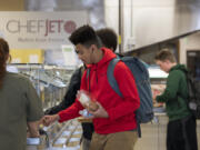 Freshman DeAndre Hampton, 15, listens to music as he picks up a meal after school at Evergreen High School on Tuesday afternoon. Students receive free meals after school to help fuel them for their evening activities.