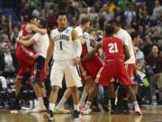 Villanova guard Jalen Brunson (1) leaves the court as Wisconsin players celebrate the end of their second-round game in the men's NCAA college basketball tournament, Saturday, March 18, 2017, in Buffalo, N.Y. Wisconsin won 65-62.