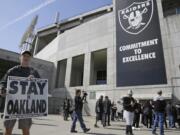 John P. Kelleher holds up a sign outside the Oakland Coliseum before the start of a rally to keep the Oakland Raiders from moving Saturday, March 25, 2017, in Oakland, Calif. NFL owners are expected to vote on the team's possible relocation to Las Vegas on Monday or Tuesday at their meeting in Phoenix.