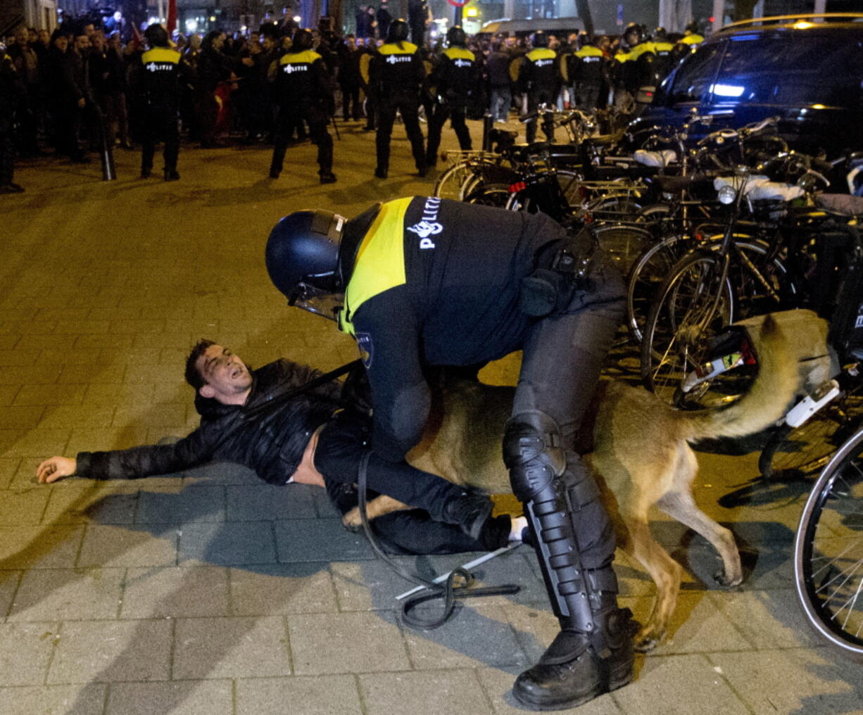 A Dutch riot policeman tries to get his dog to let go of a man after riots broke out during a demonstra-tion in support of Turkish President Recep Tayyip Erdogan early today at the Turkish consulate in Rotterdam, Netherlands.