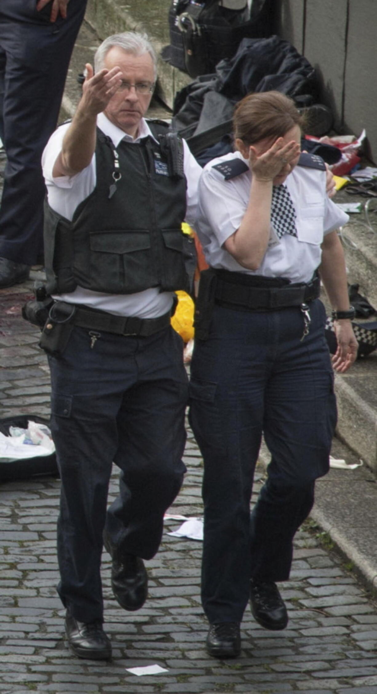 A police officer is led away by a colleague at the scene of Wednesday&#039;s attack near Britain&#039;s Houses of Parliament in London. Five people were killed when an assailant in a car mowed down pedestrians and later stabbed a police officer.