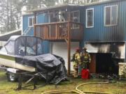 Firefighters discuss the damage after extinguishing a shop fire at this home north of La Center on Sunday morning.