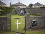 People gather June 7, 2014, at the site of a mass grave for children who died in the Tuam mother and baby home, in Tuam, County Galway. Forensics experts say they have found a mass grave for young children at a former Catholic orphanage in Ireland where suspicions of unrecorded, unmarked burials have lingered for decades.