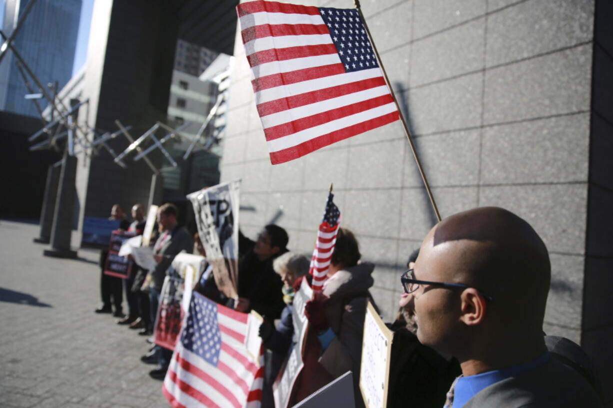 Americans and other expatriates hold some banners and U.S. flags near the U.S. Embassy in Tokyo on Thursday.