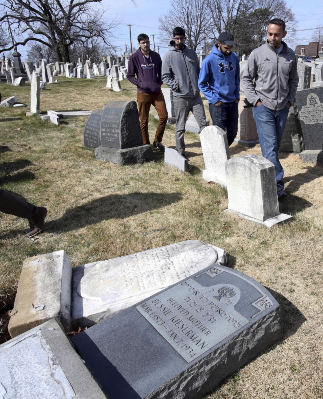 Volunteers from the Ahmadiyya Muslim Community survey damaged headstones at Mount Carmel Cemetery in Philadelphia. More than 100 headstones have been vandalized at the Jewish cemetery, discovered less than a week after similar vandalism in Missouri, authorities said.