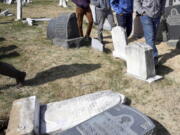 Volunteers from the Ahmadiyya Muslim Community survey damaged headstones at Mount Carmel Cemetery in Philadelphia. More than 100 headstones have been vandalized at the Jewish cemetery, discovered less than a week after similar vandalism in Missouri, authorities said.