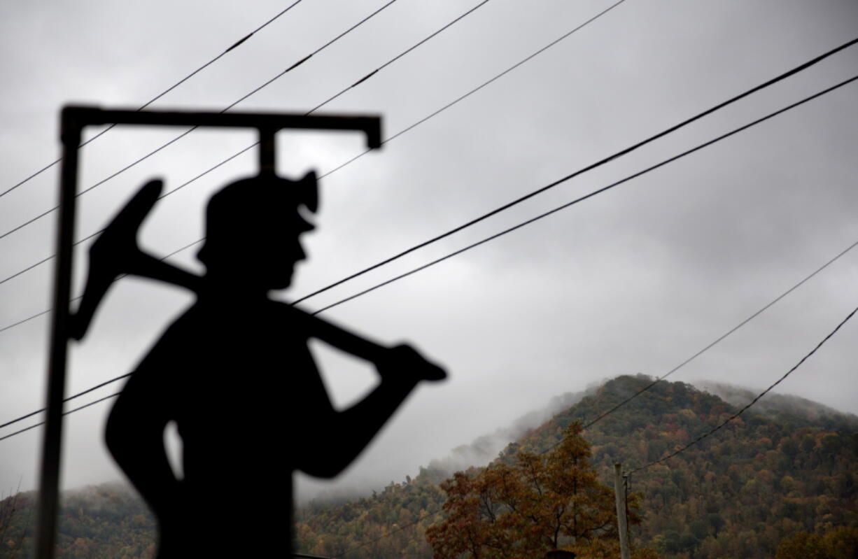 Fog hovers over a mountaintop as a cutout depicting a coal miner stands at a memorial to local miners killed on the job in Cumberland, Ky.